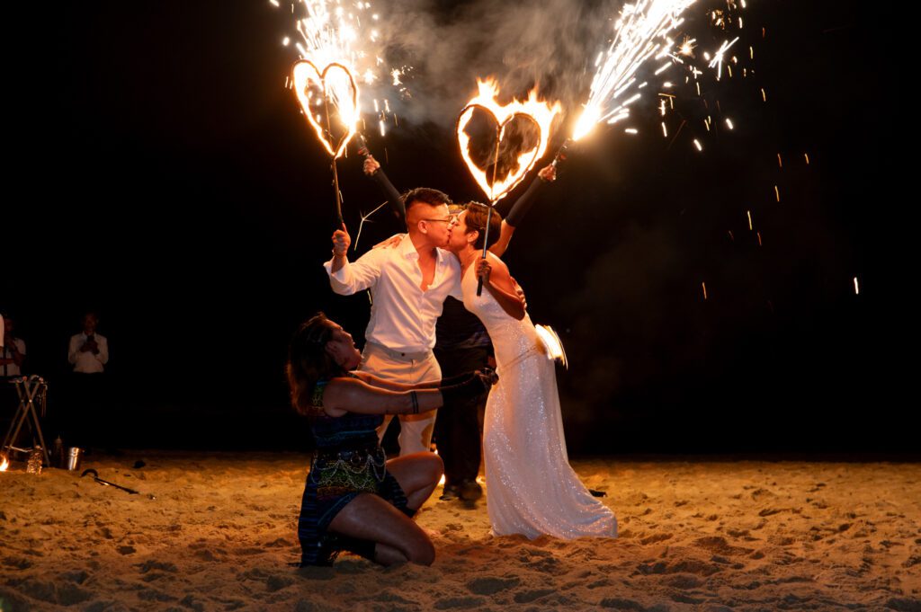 Couple celebrating with handheld sparklers during a nighttime beach wedding in Vietnam