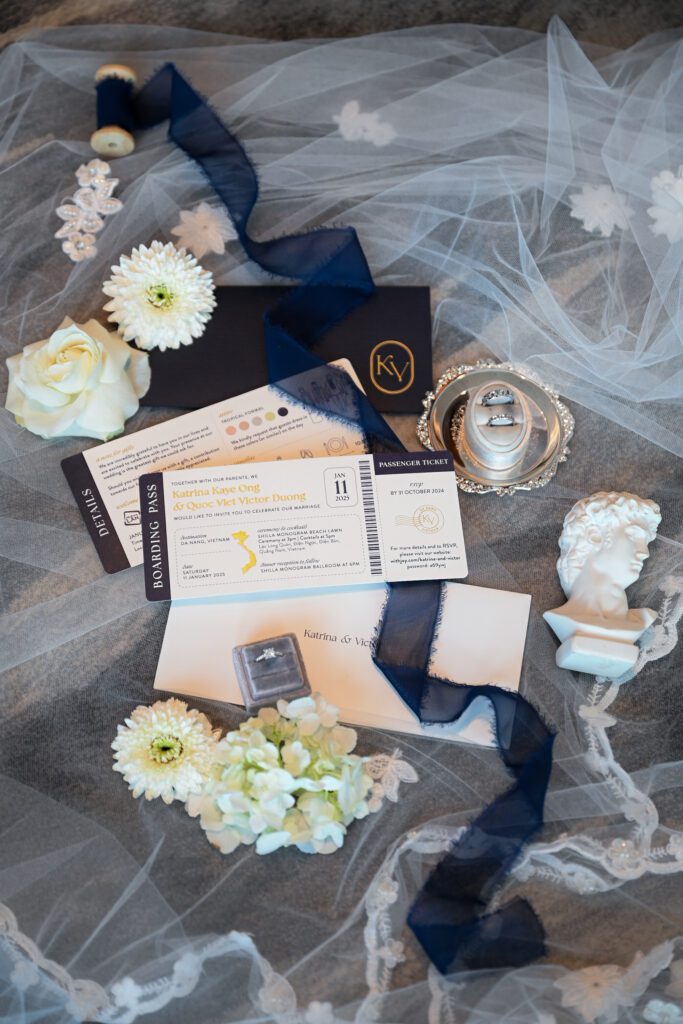 English destination wedding invitation suite with boarding pass design, rings, flowers and navy ribbon