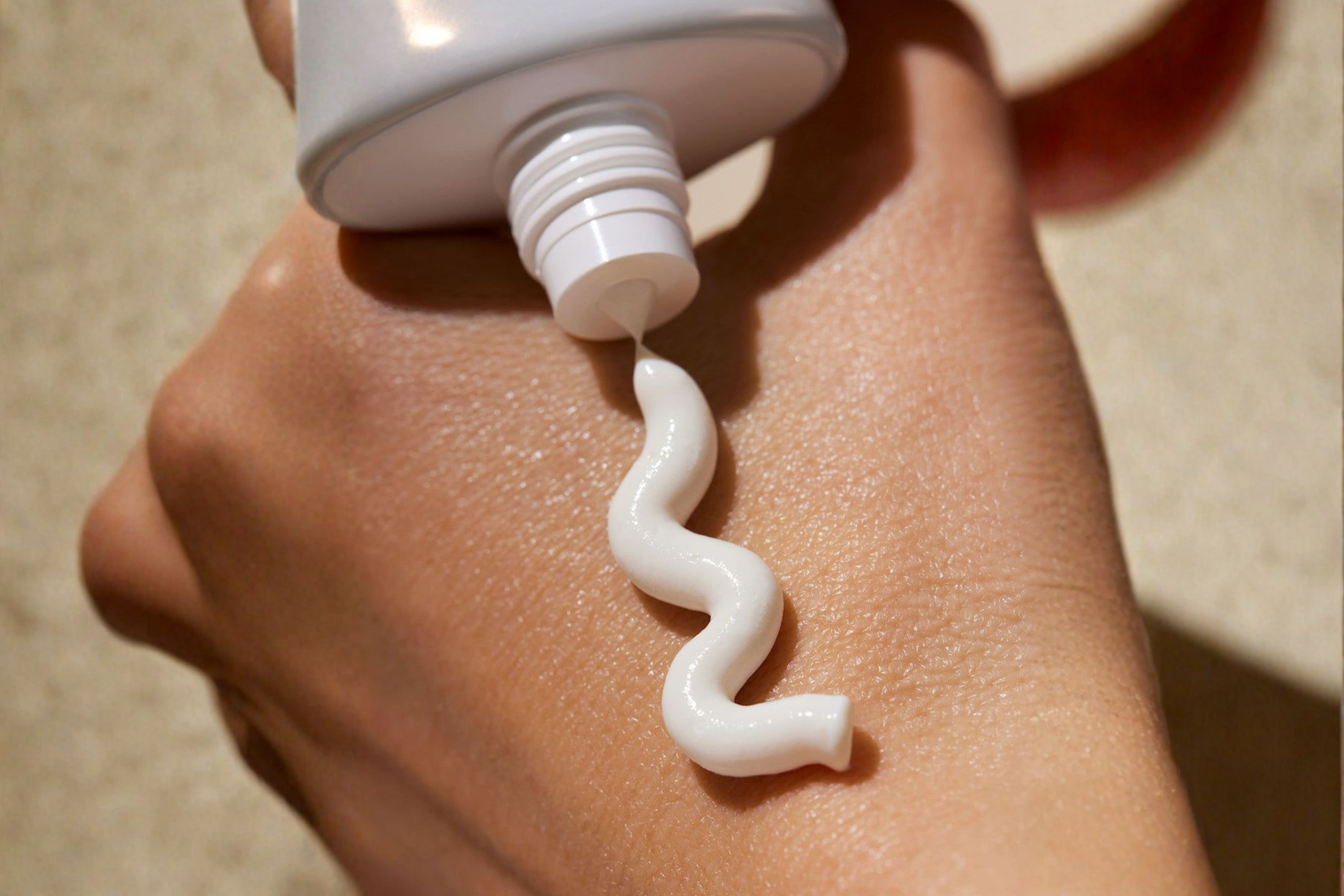 Hand on skin applying organic sunscreen, a thoughtful personal care gift for beach weddings.