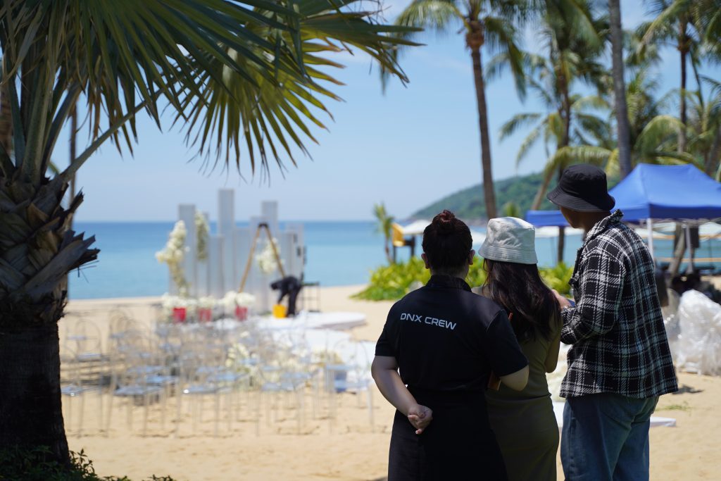A Danang-Based Wedding Planner reviewing a beachfront ceremony setup with a couple before the wedding